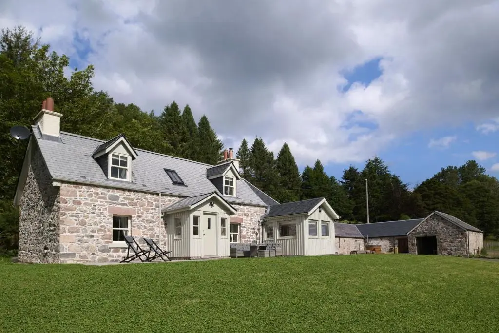 a large stone house with a grass yard at Middleton Farmhouse in Inverness