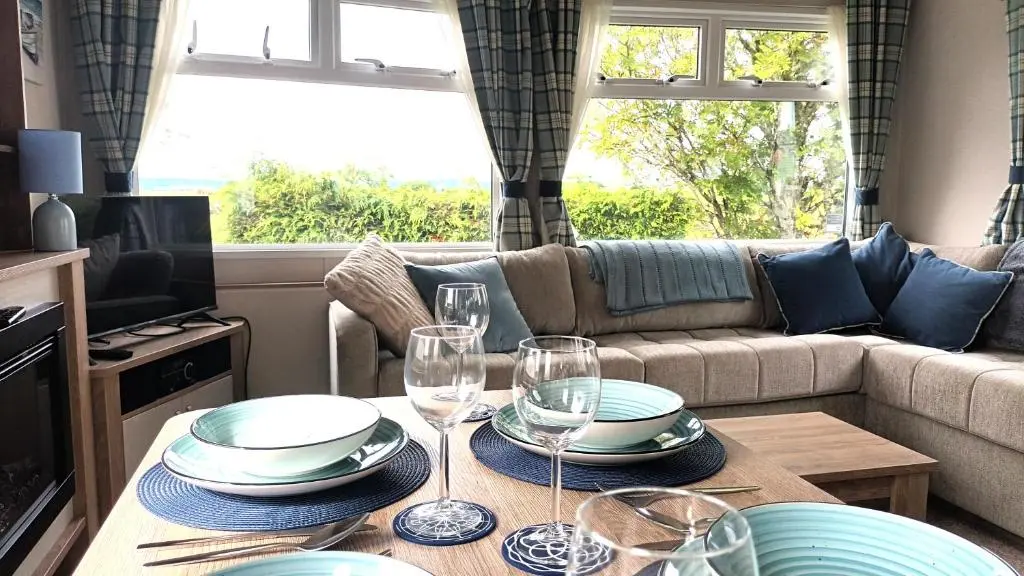 a living room with a table with plates and wine glasses at Suki - up to 6 berth cabin, new. in Tain