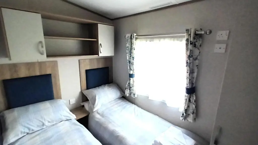 a small room with two beds and a window at Suki - up to 6 berth cabin, new. in Tain
