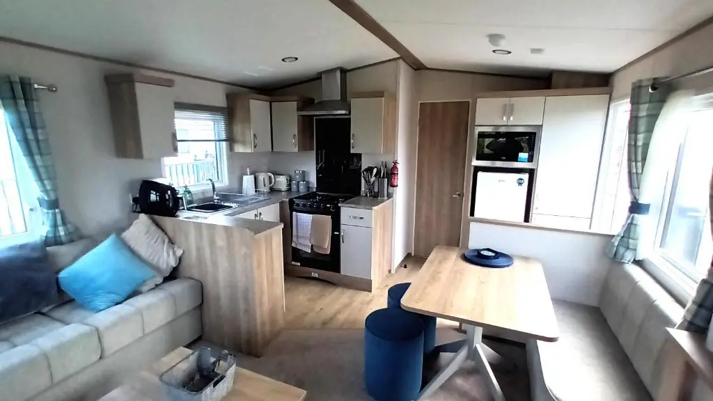 a small living room with a couch and a kitchen at Suki - up to 6 berth cabin, new. in Tain