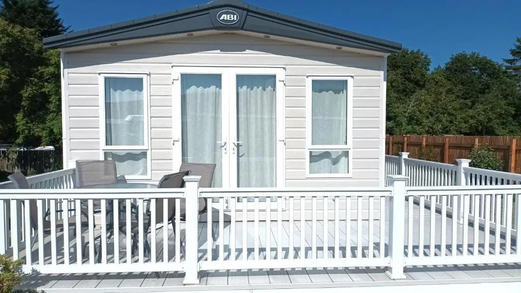 a small white house with a white fence at Binka - Luxury 40 x 14ft Lodge in Tain