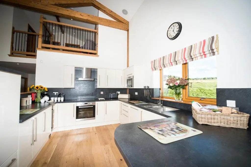 a kitchen with white cabinets and a clock on the wall at Aurae in Nairn