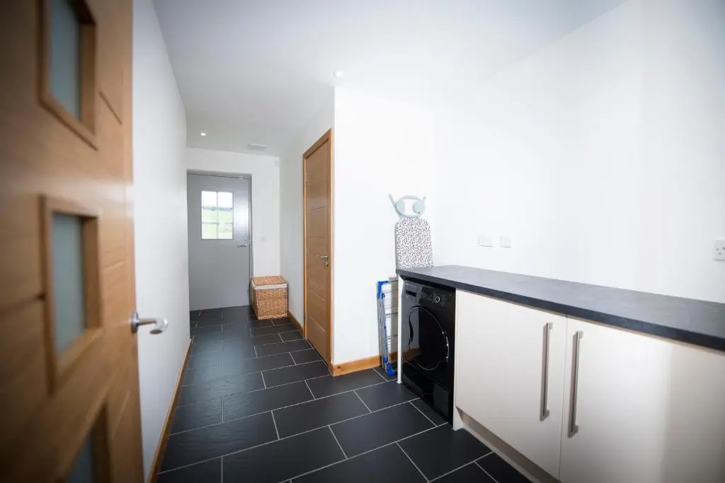 a kitchen with a black tile floor and a hallway at Aurae in Nairn