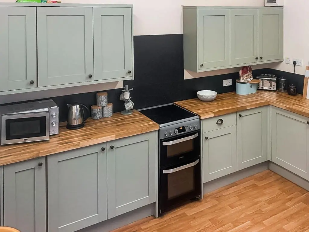 a kitchen with white cabinets and a stove top oven at Gleneffock Farmhouse in Tarfside