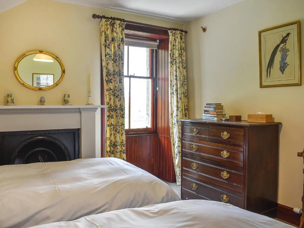 a bedroom with a bed and a dresser and a mirror at Gleneffock Farmhouse in Tarfside