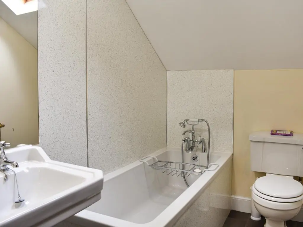 a white bathroom with a toilet and a sink at Gleneffock Farmhouse in Tarfside