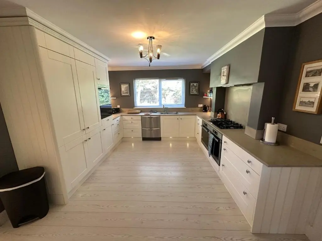 a large kitchen with white cabinets and a hardwood floor at Cardon House - luxury Highland holiday home in Inverness
