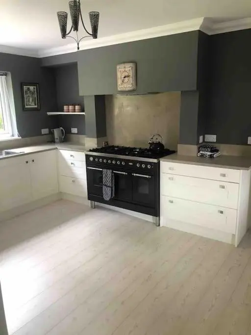 a kitchen with a black stove and white cabinets at Cardon House - luxury Highland holiday home in Inverness