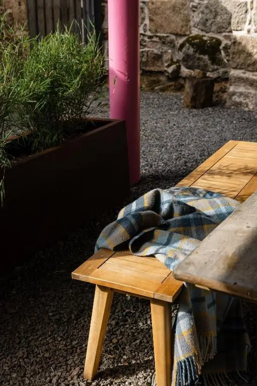 a plaid blanket sitting on a wooden bench at The Hayloft in Banchory