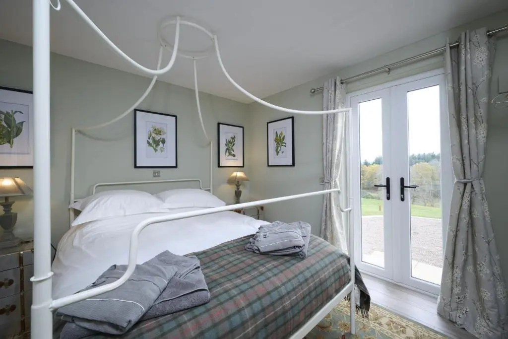 a bedroom with a white bed and a window at Balnacraig Farmhouse in Inverness