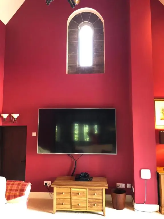 a room with a red wall with a flat screen tv at The Highland Club in Fort Augustus
