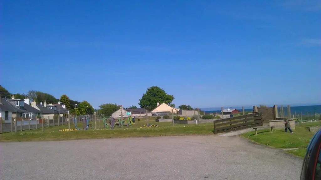 a park with a fence and houses and the ocean at Sunnyside Cottage 2 Bedrooms 1 Bathroom 1 WC 2 Pets Welcome in Hilton of Cadboll
