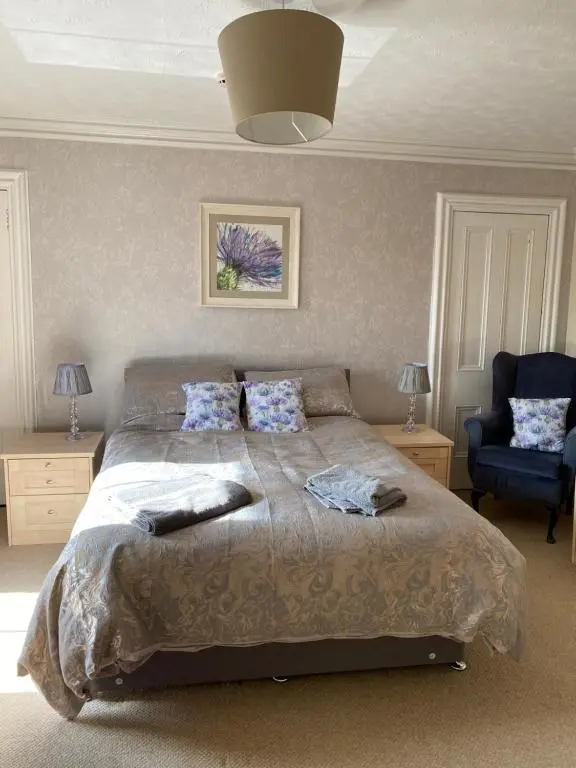 a bedroom with a large bed and a blue chair at 47 High Street in Alness