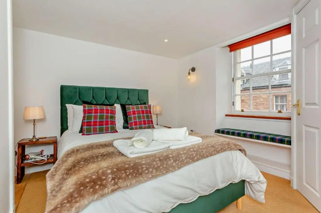 a bedroom with a large bed with a green headboard at Jacobite's Retreat, 17th century cottage in the heart of Inverness in Inverness