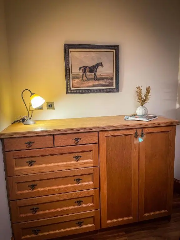 a dresser with a picture of a horse on the wall at Cathedral Apartment in Inverness