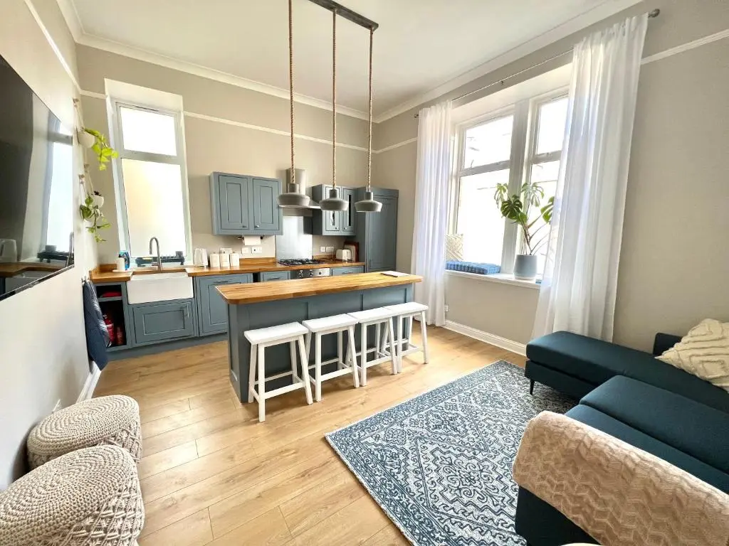 a living room with a couch and a kitchen at Lossie Self-Catering Apartment in Lossiemouth