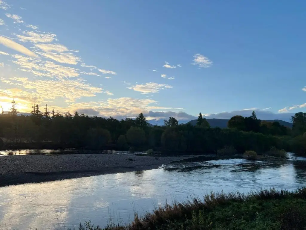 a view of a river with the sun setting at Silver Birch Lodge Aviemore in Aviemore