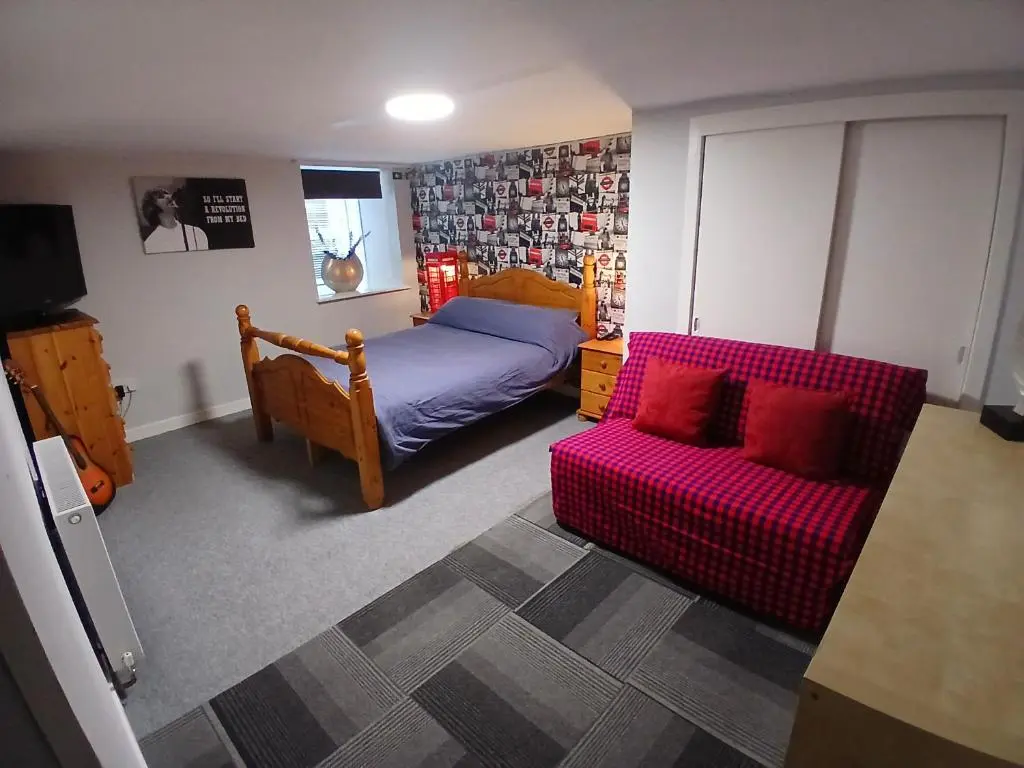 a bedroom with a bed and a red couch at The Hideaway Inverurie in Inverurie