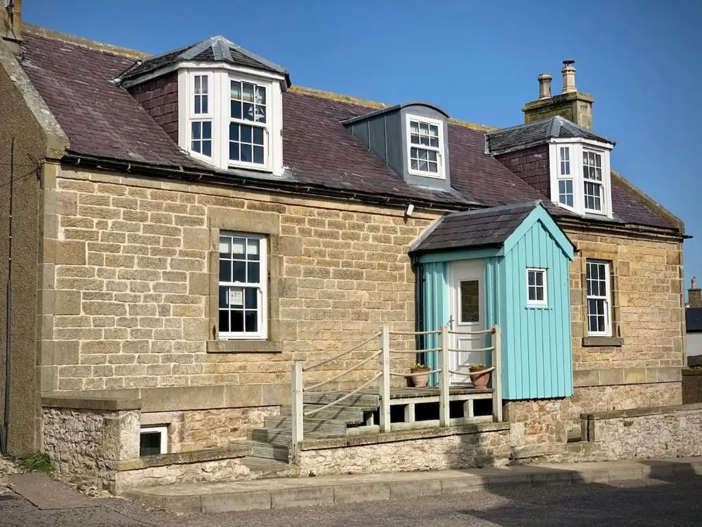 a house with a blue shack on the side of it at The Millie Luxury Five Star with Sea View in Burghead