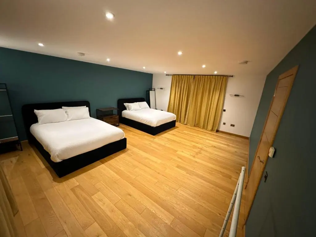 two beds in a room with wooden floors at 1 Woodside in Elgin