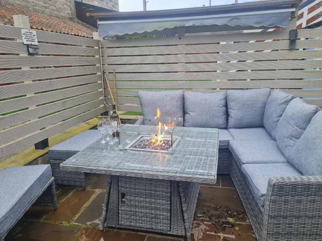 a patio with a couch and a table with a fire at Cullen Holiday Home in Cullen