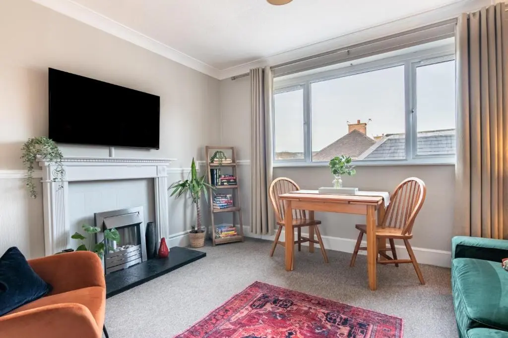 a living room with a table and a fireplace at Sweet Ness River Flat in Inverness