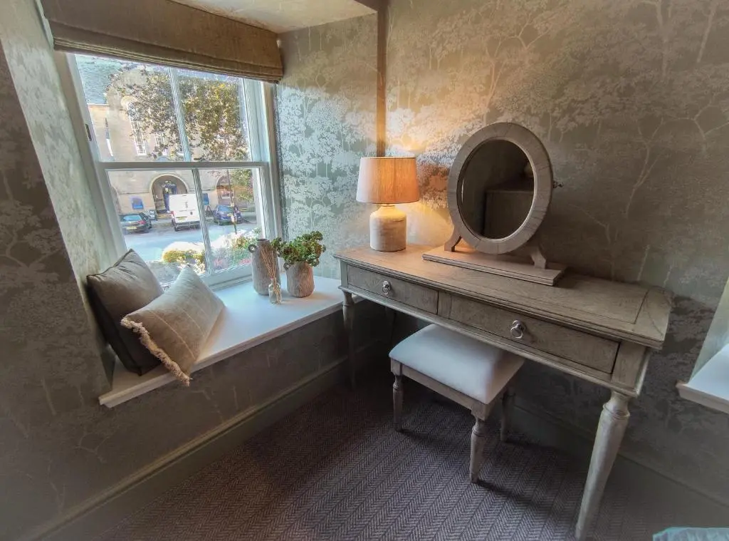 a dressing table with a mirror and a lamp on a window at Cathedral House in Dornoch