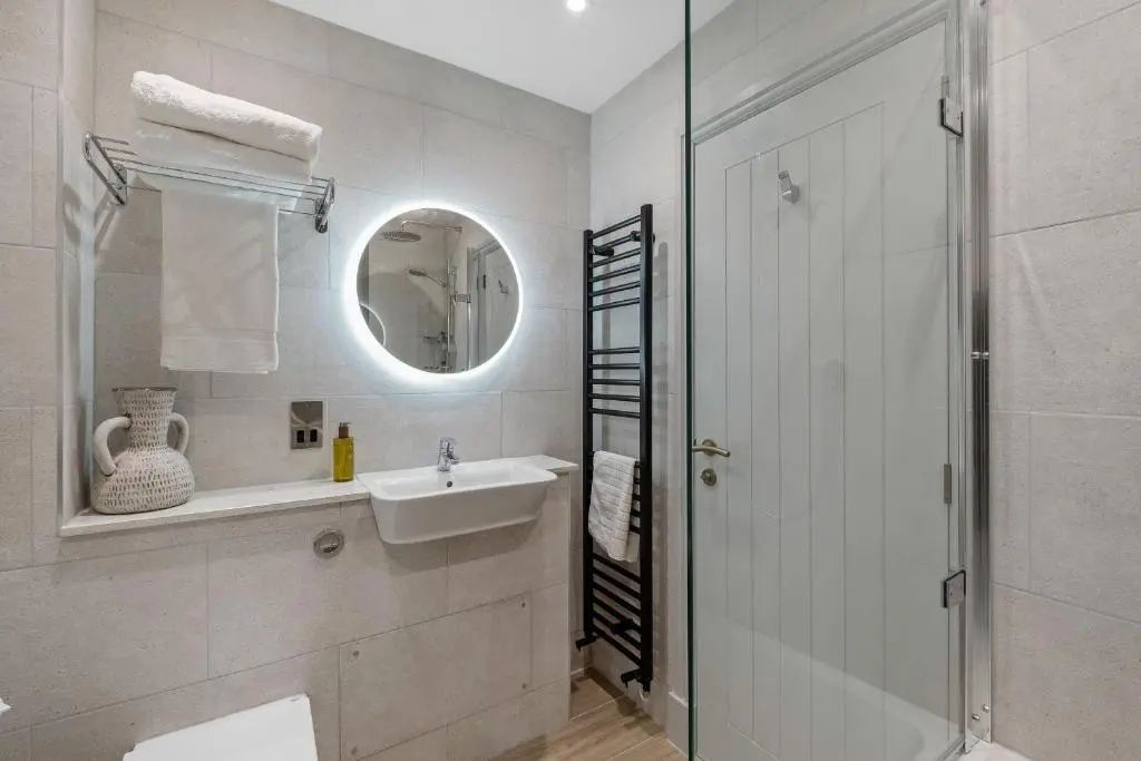 a white bathroom with a sink and a shower at Cathedral House in Dornoch