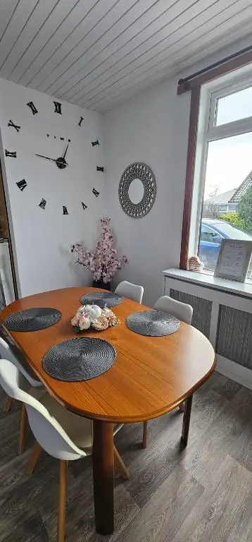 a dining room table with chairs and a clock on the wall at Westview in Buckie