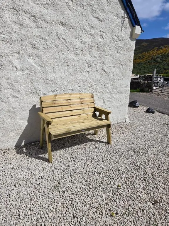 a wooden bench sitting next to a white wall at 176 Marrell in Helmsdale