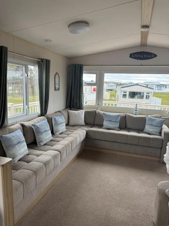 a large couch in a living room with windows at Beach life in Lossiemouth