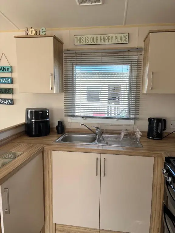 a kitchen with a sink and a sign that reads this is our happy place at Beach life in Lossiemouth