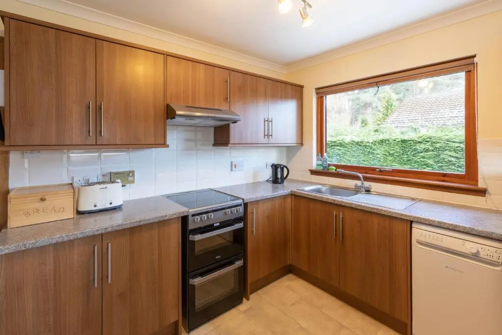 a kitchen with wooden cabinets and a window at Aonach in Kingussie