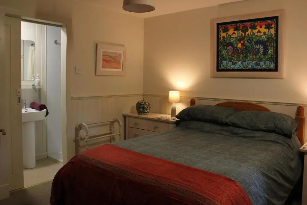 a bedroom with a bed and a sink at Smithy Cottage in Strathdon