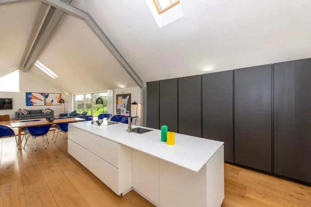 a kitchen with a white counter and blue chairs at Architect Designed Lodge in Dunecht