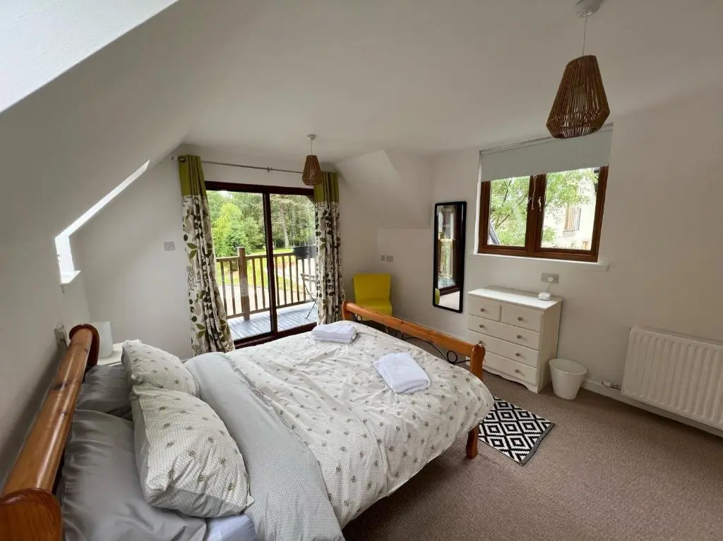 a bedroom with a large bed and a balcony at Birchwood Cottage in Tore