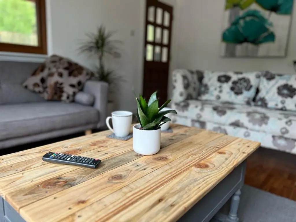 a wooden table in a living room with a remote control at Birchwood Cottage in Tore