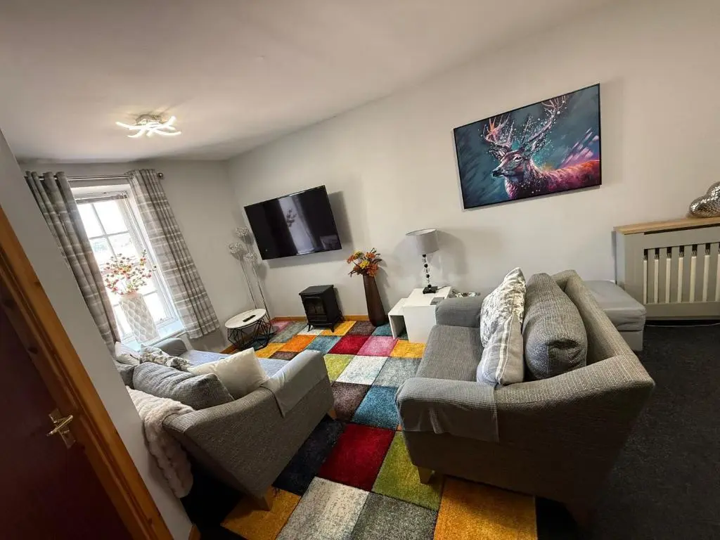 a living room with two couches and a colorful rug at Old Dairy in Tain