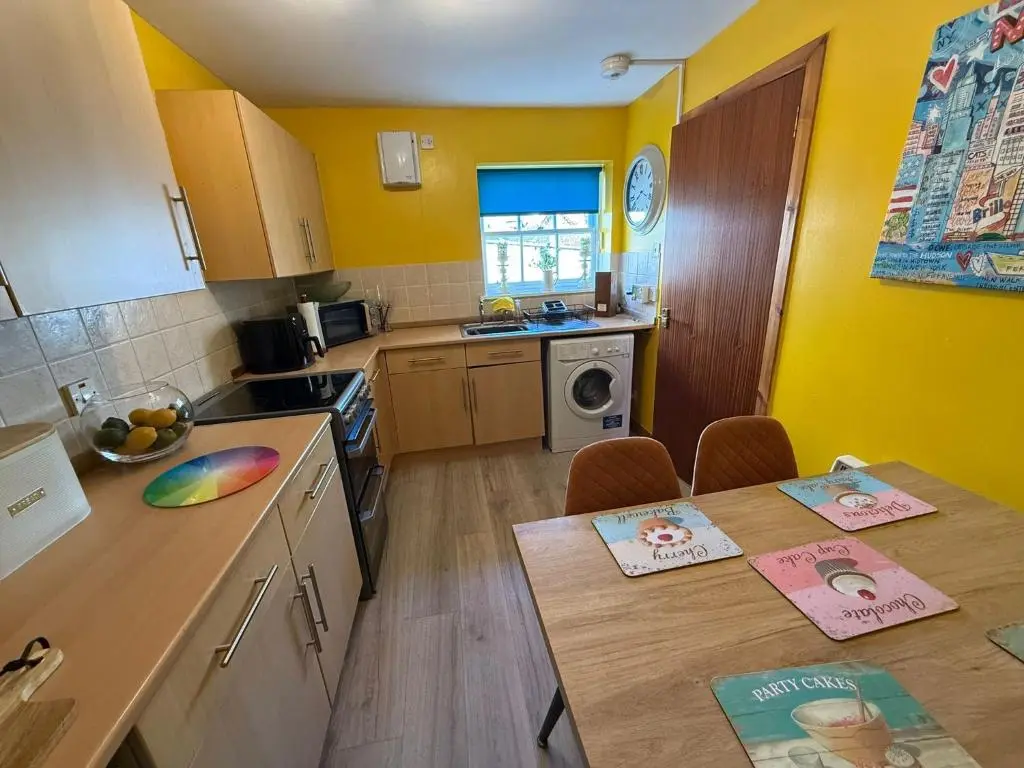 a kitchen with yellow walls and a table and chairs at Old Dairy in Tain
