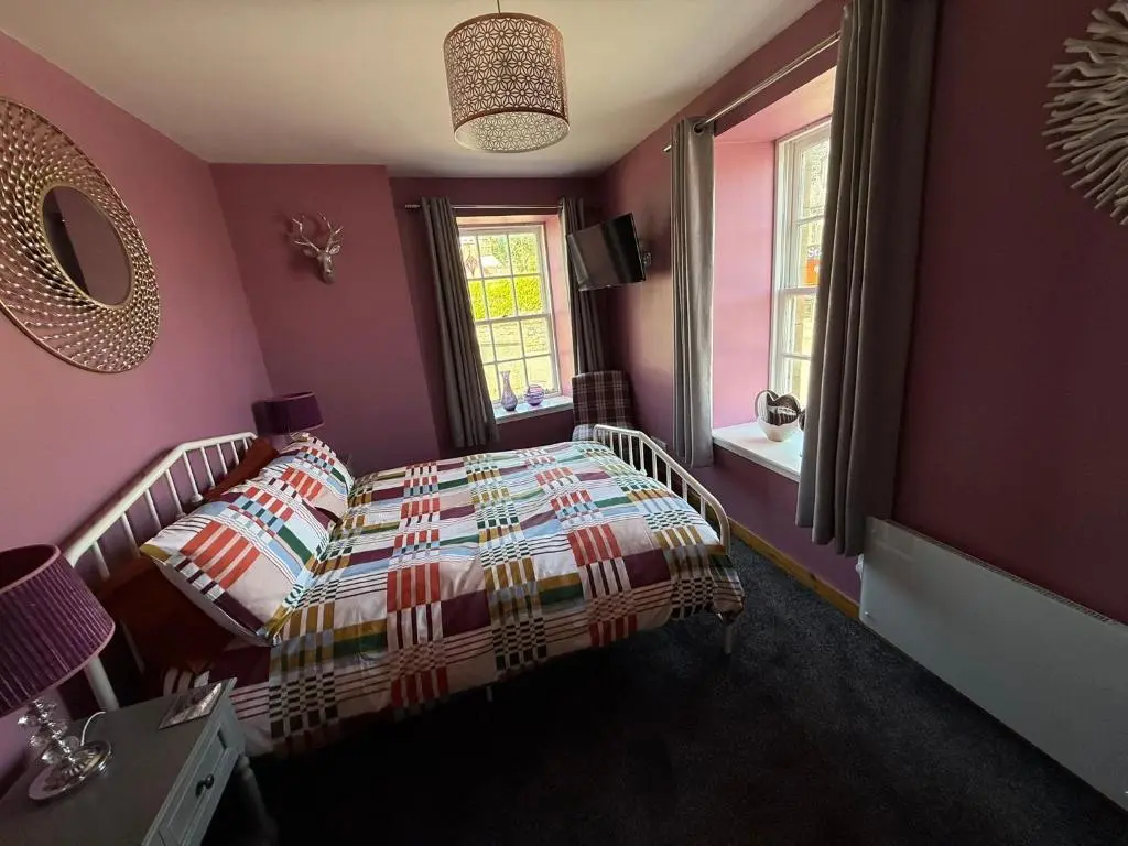 a bedroom with a bed and purple walls at Old Dairy in Tain