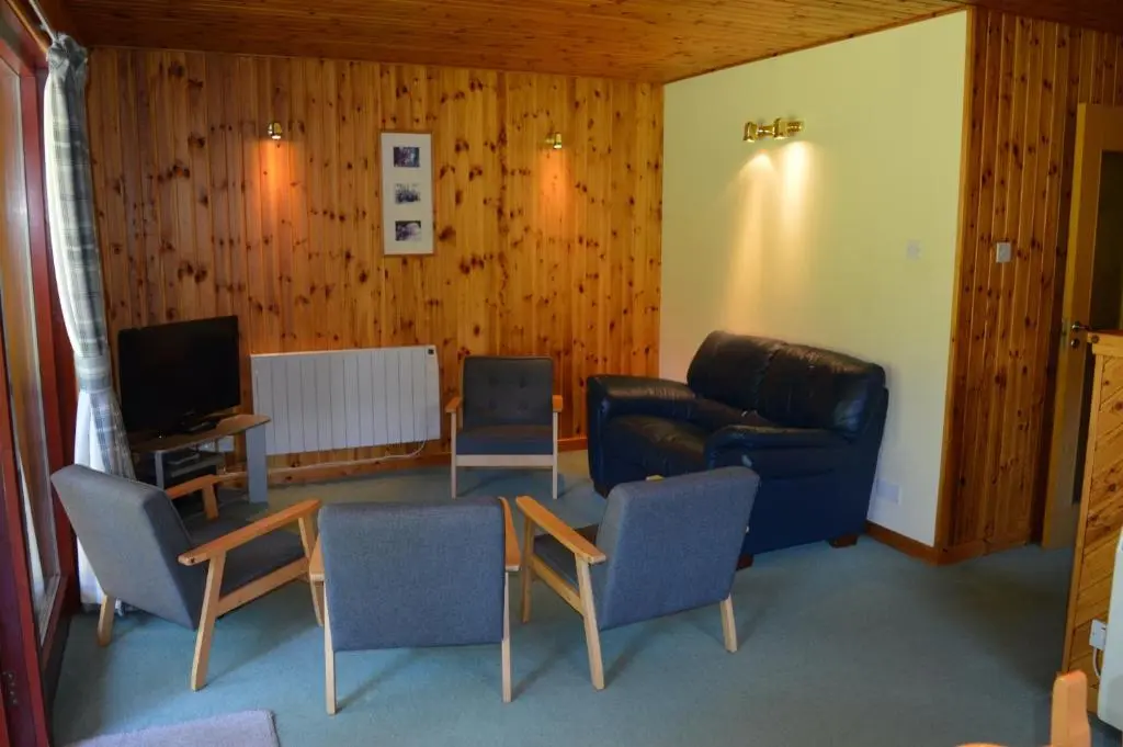 a living room with a couch and chairs and a television at Reuben's Highland Retreat - Speyside in Carrbridge
