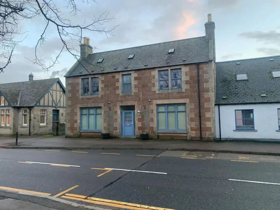 a brick building with a blue door on a street at The old post office in Golspie