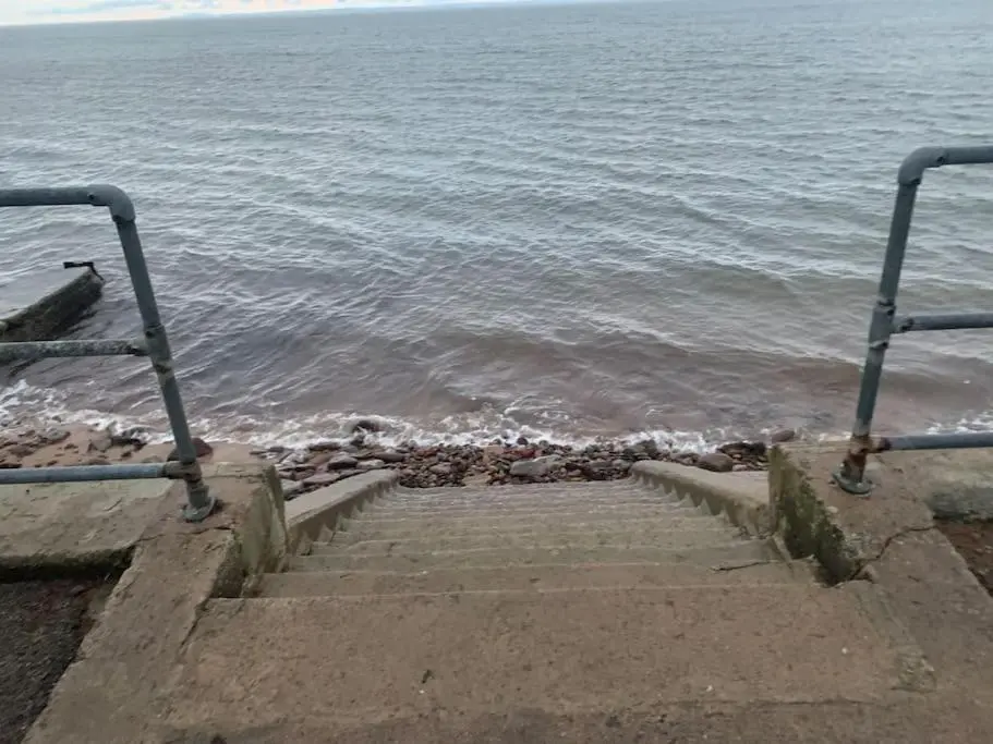 a set of stairs leading to the ocean with the waves at The old post office in Golspie