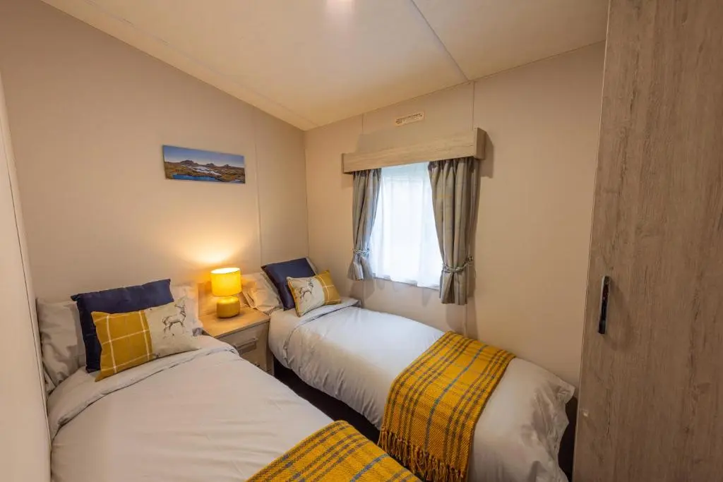 two beds in a small room with a window at Highland Chalet - Peaceful Stay near Dornoch in Dornoch