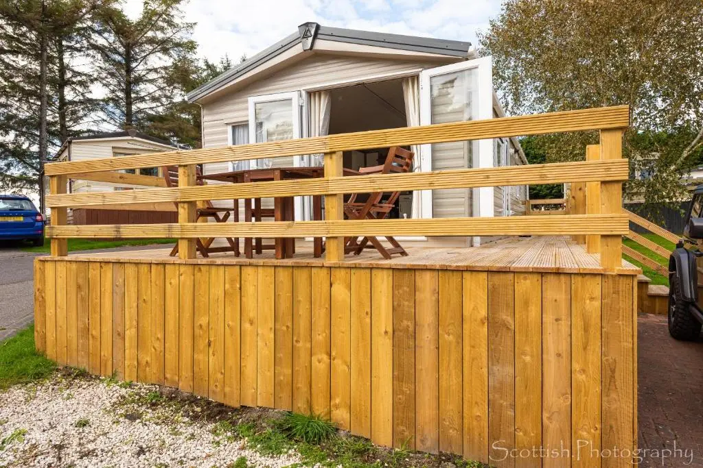 a wooden fence in front of a house at Highland Chalet - Peaceful Stay near Dornoch in Dornoch