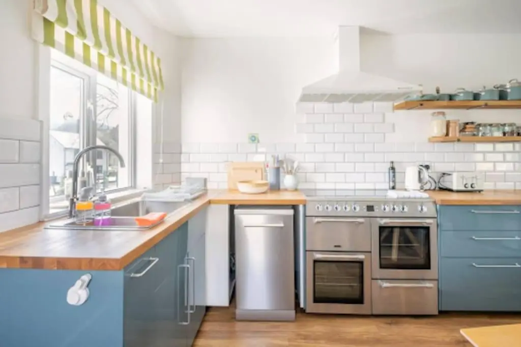 a kitchen with blue cabinets and a stainless steel oven at Cosy Hygge/ Scottish themed home by Loch Ness in Fort Augustus