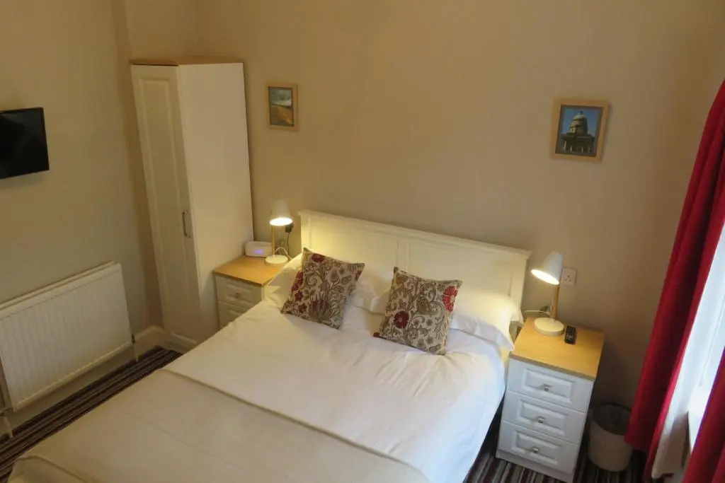 a bedroom with a white bed with two pillows at West End Guest House in Elgin