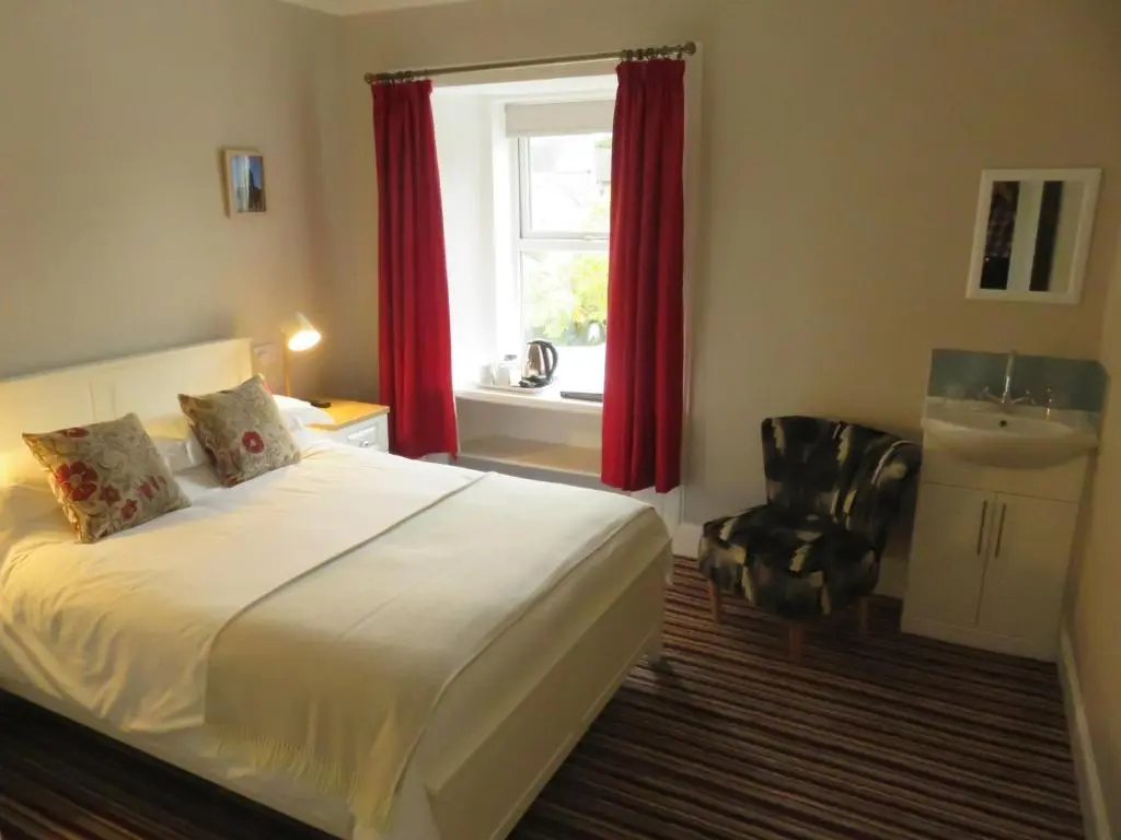 a bedroom with a bed and a window and a chair at West End Guest House in Elgin