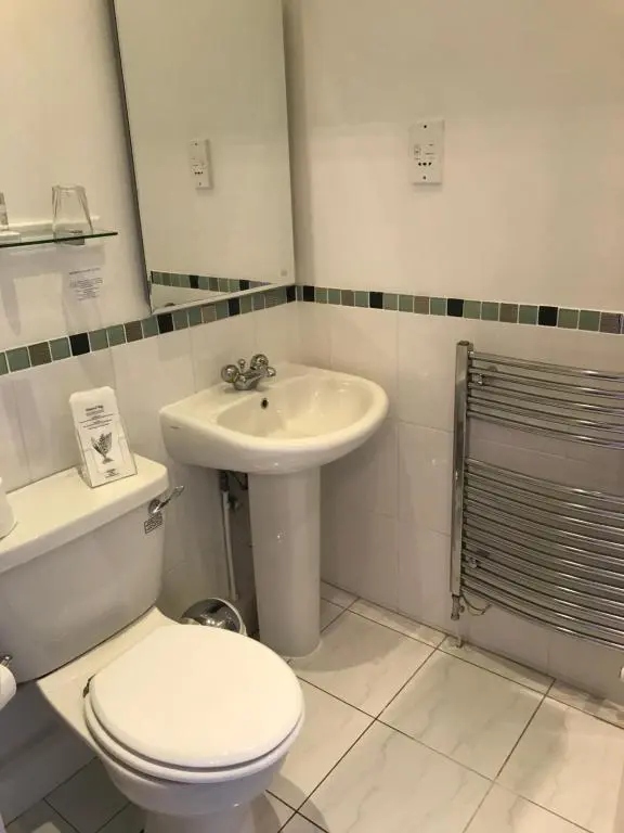 a white bathroom with a toilet and a sink at West End Guest House in Elgin