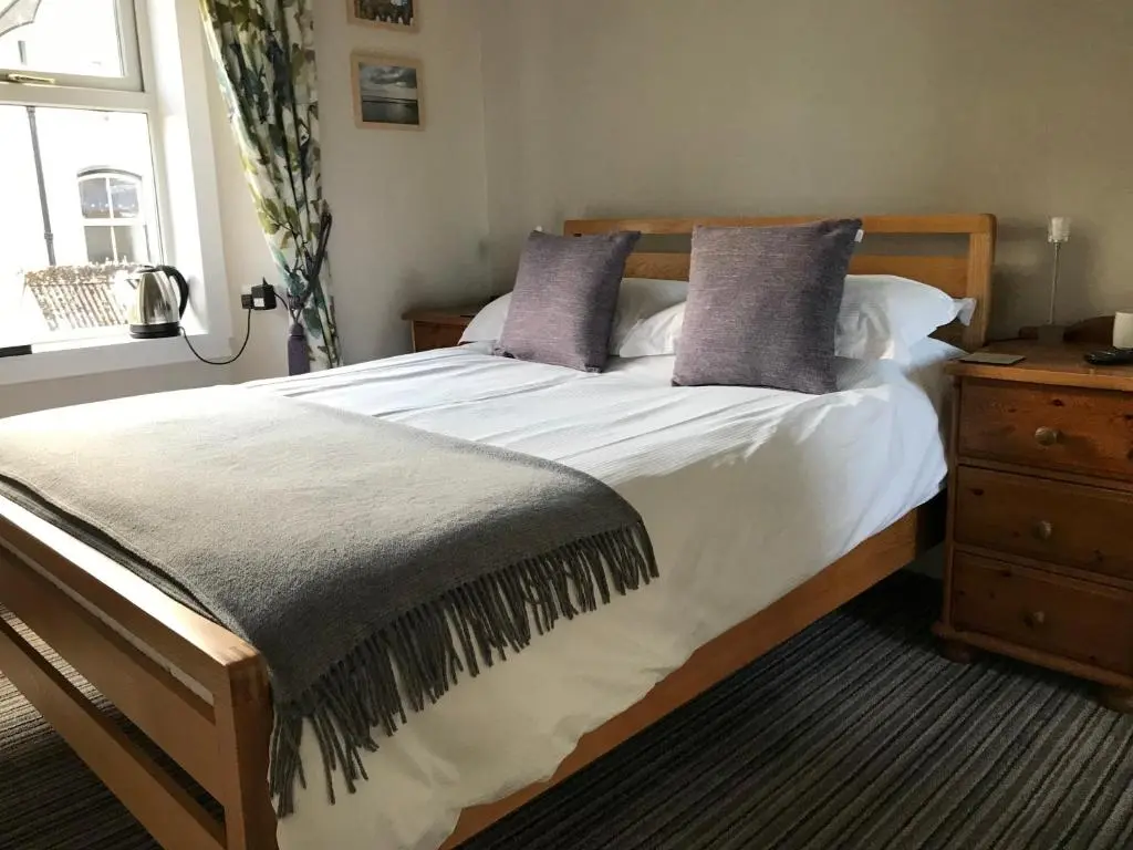 a bedroom with a large bed with purple pillows at West End Guest House in Elgin
